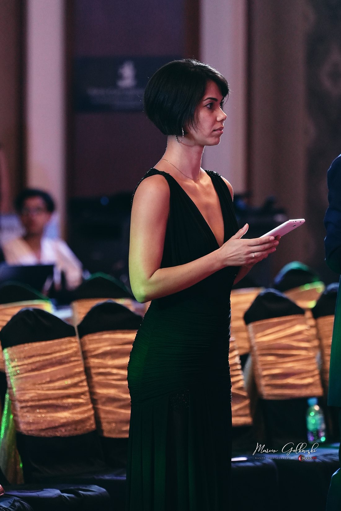 Raliza in a long green gown at the adjudicators' table during a championship