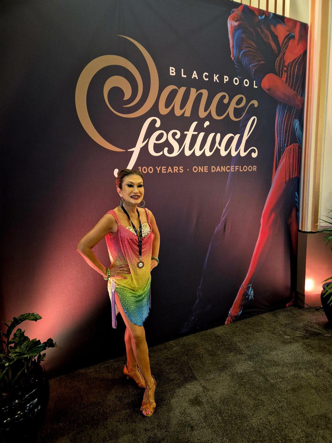 Raliza in a rainbow-coloured Latin dress with a medal at the Blackpool Dance Festival