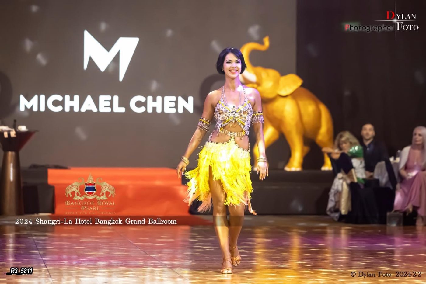 Raliza performing in a gold fringed dress on a stage decorated with golden elephants at a hotel event