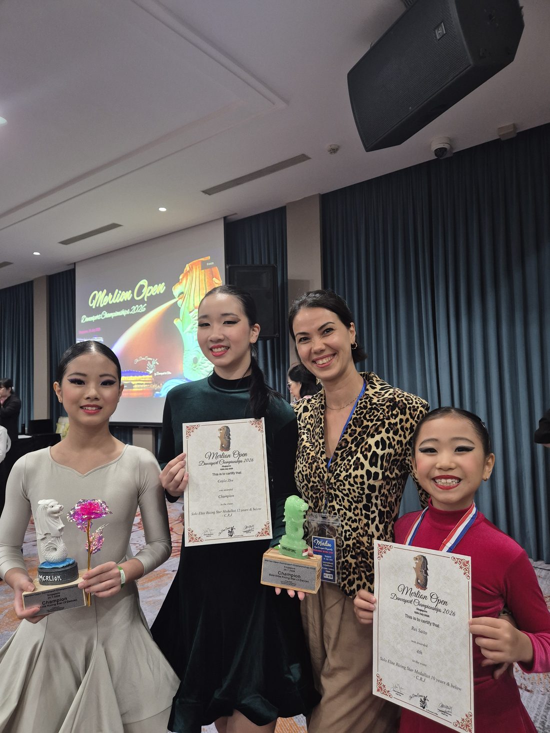 Raliza with two young students holding trophies and certificates